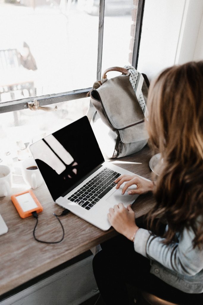 Woman working at a laptop in front of a window